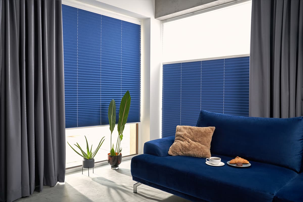 Blaue Plissees als Sicht- und Sonnenschutz an Wohnzimmerfenstern